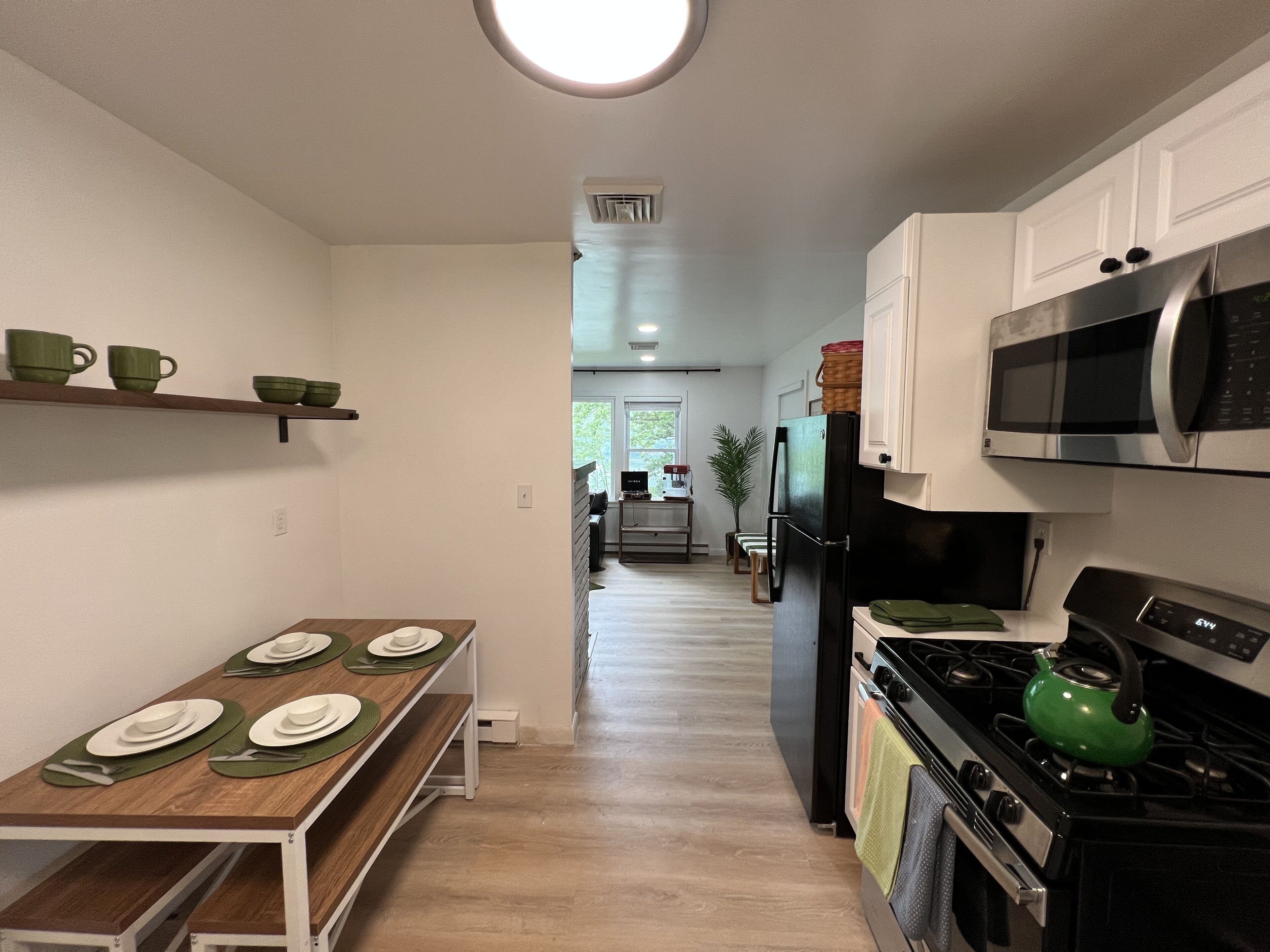 A modern kitchen with a dining table set for four, a microwave, stove, and refrigerator.