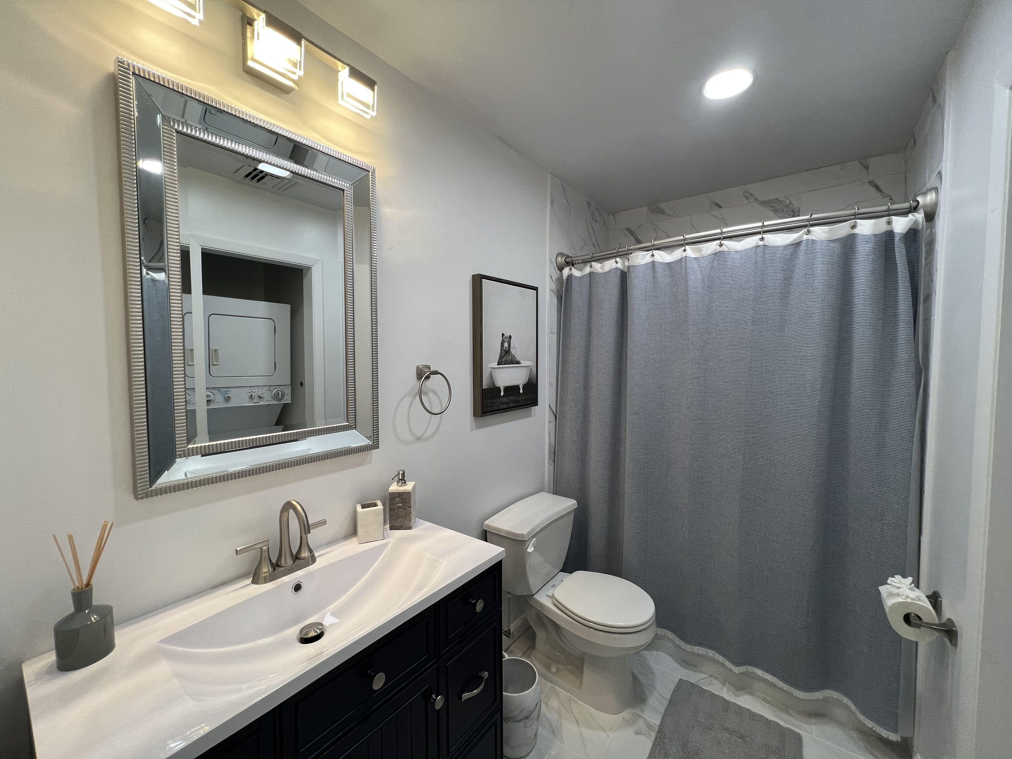 A bathroom with a vanity, sink, mirror, toilet, and shower curtain.