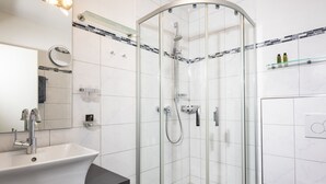 Ein modernes Badezimmer mit einer gläsernen Dusche, einem Waschbecken mit schwarzer Arbeitsplatte und einer Toilette.