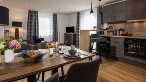 Eine moderne Küche mit dunklen Schränken, einem eingebauten Backofen und einem Essbereich mit Holztisch und Stühlen.