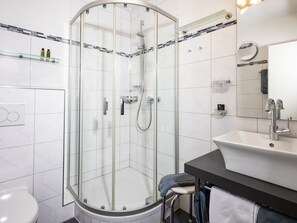 A modern bathroom with a glass-enclosed shower, a white sink, and a mirror above it.