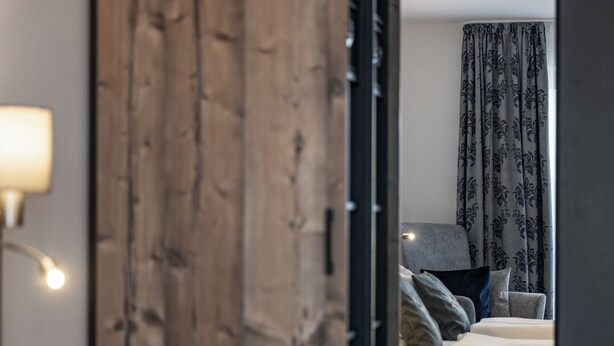A bedroom with a bed, pillows, a lamp, and a curtain.