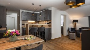 A modern kitchen with dark cabinets, a wooden dining table, and bar stools.