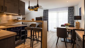 A modern kitchen with wooden countertops, a built-in oven, and a dining area with a wooden table and bar stools.
