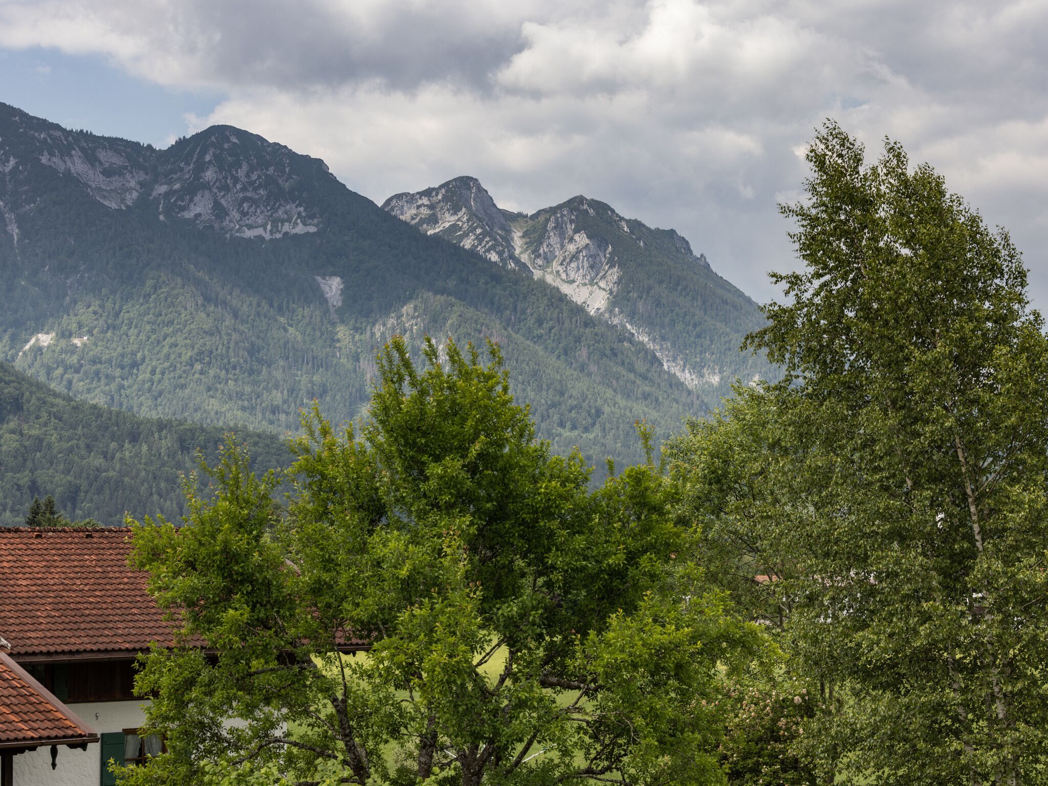 A mountain landscape with a house in the foreground.