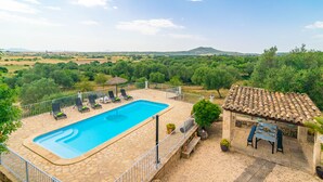 A swimming pool with lounge chairs, a pergola, and a view of the countryside.