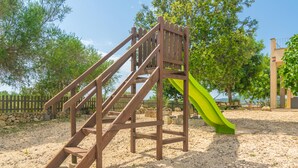 A wooden play structure with a slide in a park setting.