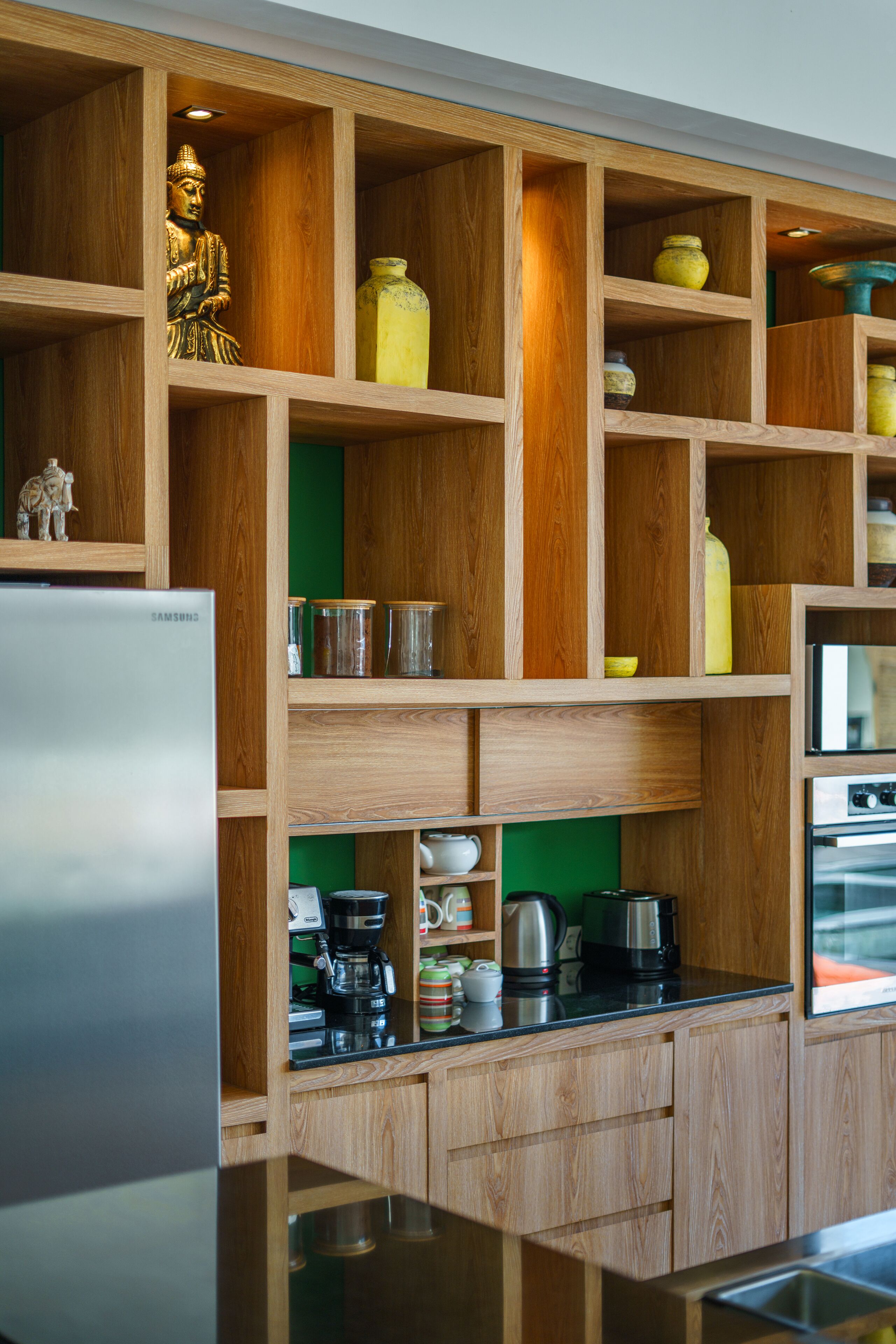 A kitchen with wooden shelves, a refrigerator, and various kitchen appliances.