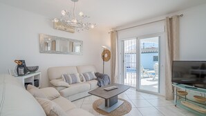 Una sala de estar moderna con sofá, mesa de centro, televisor y un balcón con vistas.