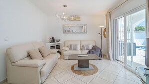 Una sala de estar moderna con un sofá, una mesa de centro y un ventanal con vista a una piscina.