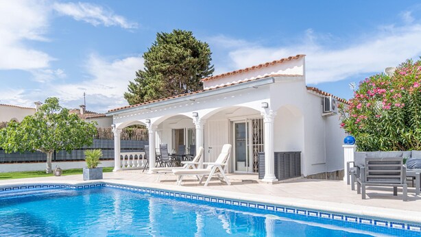 Un área junto a la piscina con una zona de estar cubierta, piscina y vistas del paisaje circundante.