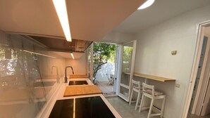A modern kitchen with a central island, a sink, and a dining area with chairs.