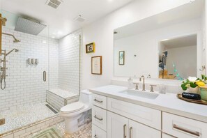 Een moderne badkamer met een ruime douche, een grote spiegel en een wastafelmeubel met een wastafel.