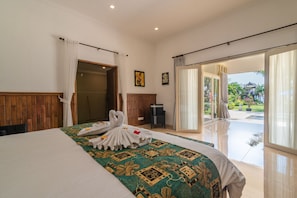 A hotel room with a large bed, a wooden headboard, a glass door leading to a balcony, and a view of the outdoors. - Villa Hikume (Banjar)