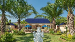 Un resort con un edificio a tetto blu, palme e una statua sullo sfondo.
