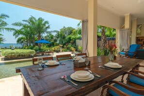 A dining area with a view of the sea, outdoor seating, and a pool. - Villa Hikume (Banjar)