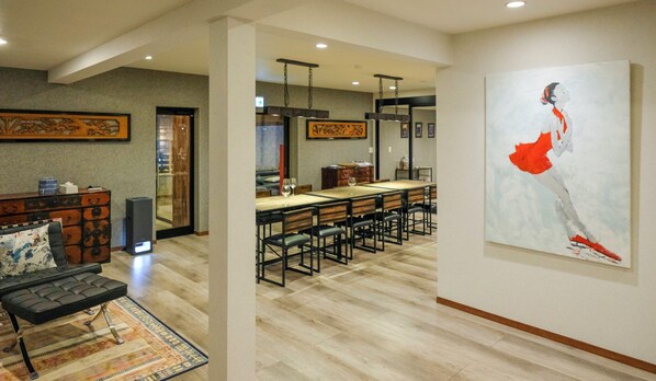 A modern dining area with a long table, chairs, and a large abstract painting on the wall.