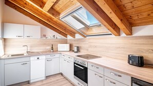 Une cuisine moderne avec des armoires blanches, des appareils en acier inoxydable et un puits de lumière.