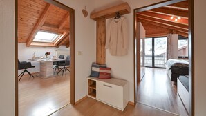 Une pièce avec un plafond en bois, un bureau avec des chaises, un banc avec des coussins et un lit.