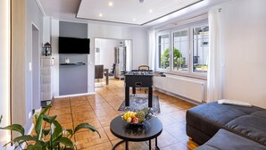 Ein modernes Wohnzimmer mit einem Kicker, einer Couch und einem Essbereich mit Tisch und Stühlen.