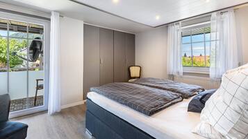 A bedroom with a bed, a chair, a wardrobe, and a window with a view.
