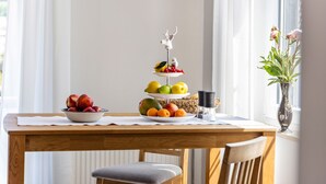 Ein Esstisch mit Obstschale, einer Etagere für Früchte und einer Vase mit Blumen.