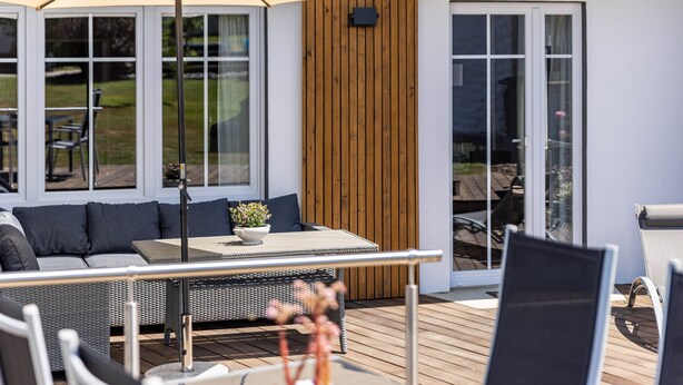 Ein moderner Sitzbereich im Freien mit Tisch, Stühlen und einem großen Sonnenschirm.