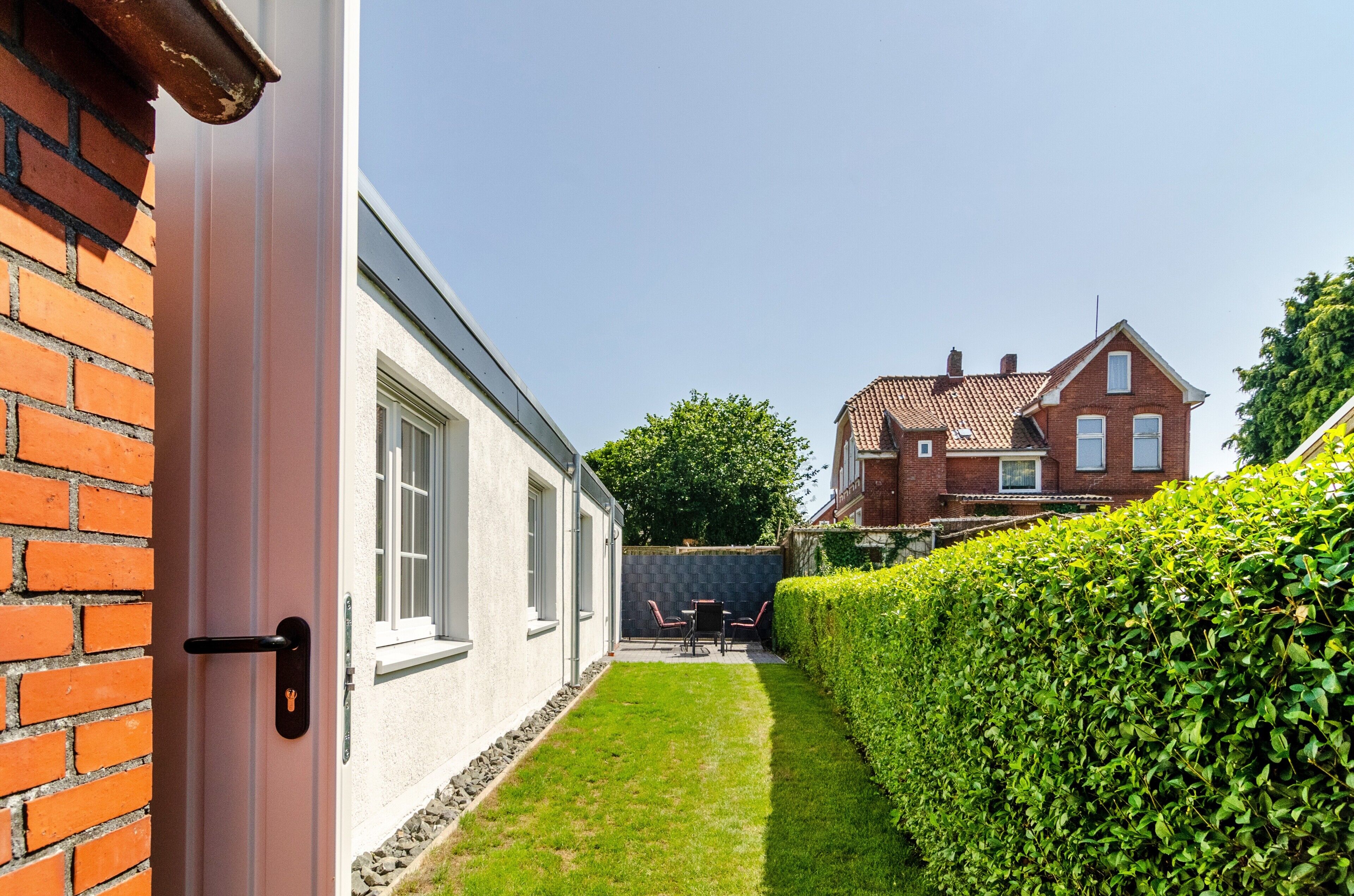 Ein Wohnhaus mit Ziegelaußenwand, gepflegtem Rasen und einer Hecke.