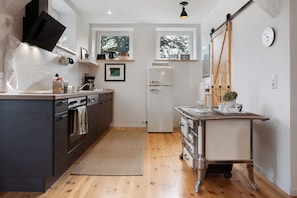A modern kitchen with a built-in oven, a refrigerator, and a dining area with a table and chairs. - Apartment "Entenfang" with Private Garden & Wi-Fi (Groß Wokern)