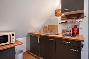A compact kitchenette with a microwave, sink, and wooden countertop. - Apartment "McIntosh" with Private Garden & Wi-Fi (Groß Wokern)