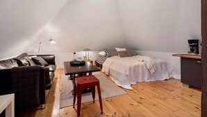 Un acogedor dormitorio tipo loft con una cama, un sofá, una mesita y una cafetera.