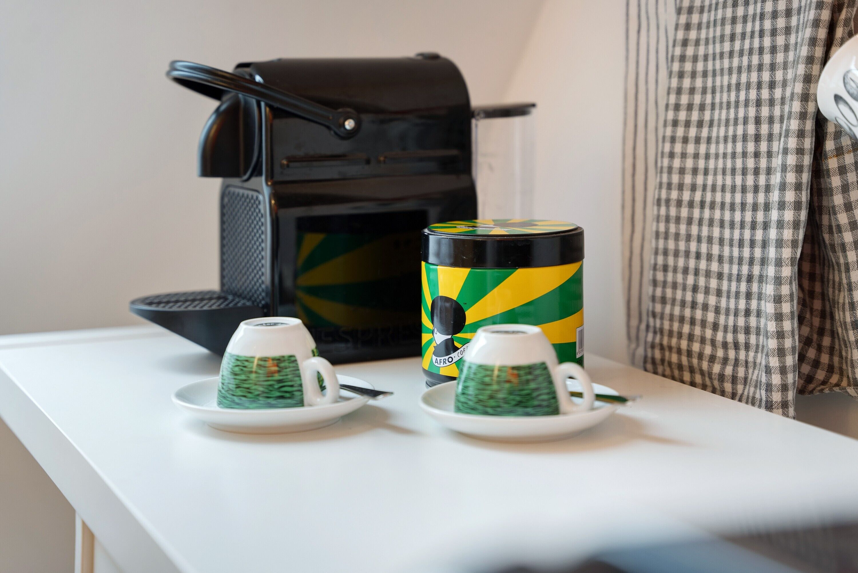 A coffee maker, two cups, and a thermos on a table.
