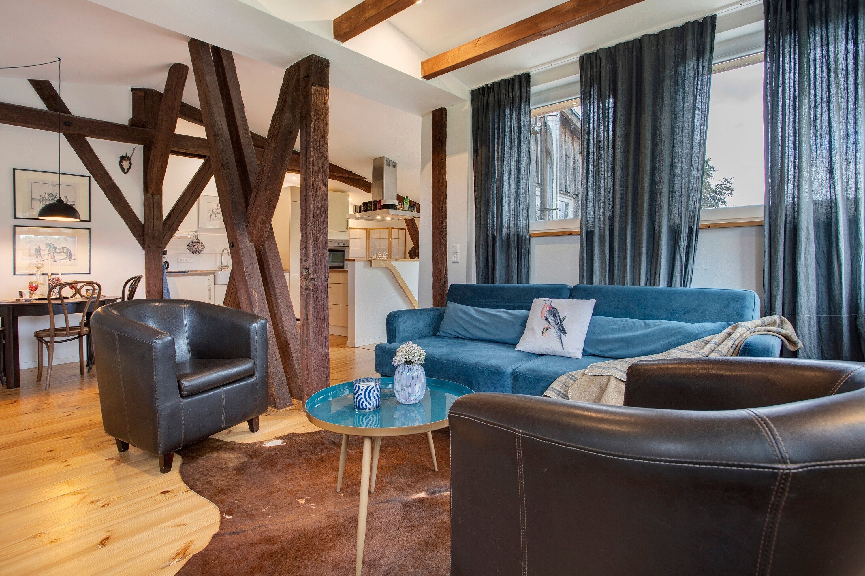 A living room with a blue sofa, a black leather armchair, and a glass coffee table.