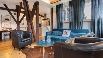 A living room with a blue sofa, a black leather armchair, and a glass coffee table.