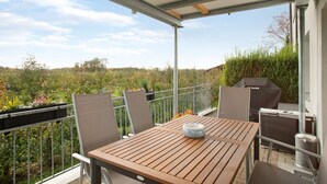 A covered outdoor patio with a table and chairs, a grill, and a view of the surrounding garden. - Holiday Apartment "FeWo Schwenck" with Shared Terrace, Shared Garden and Wi-Fi (Kressbronn am Bodensee)