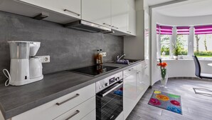 A modern kitchen with a coffee maker, oven, and a window with pink blinds.