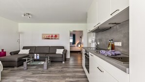A modern living room with a sofa, coffee table, and a view into the kitchen.