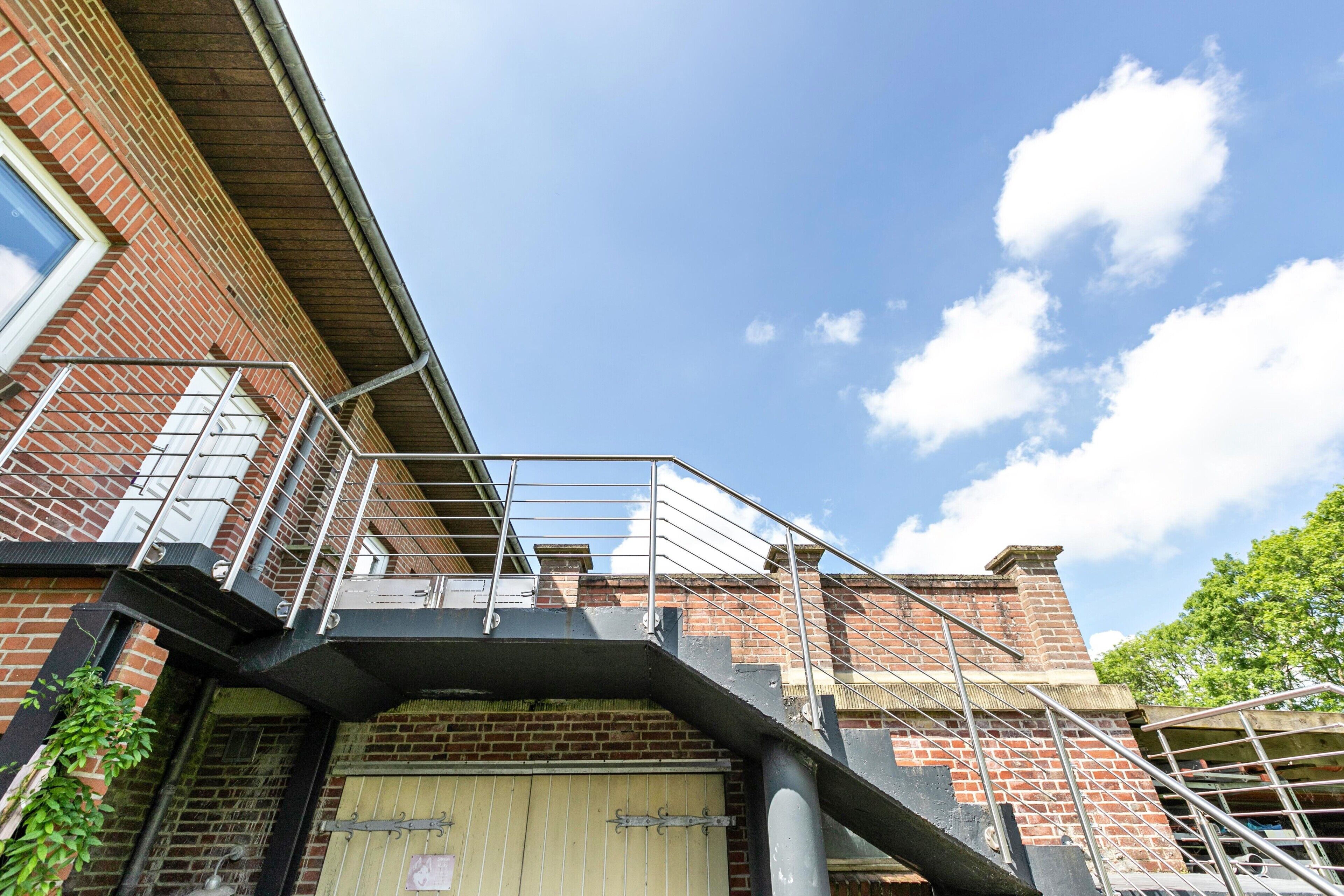A brick building with a metal staircase, a gated entrance, and a clear sky.