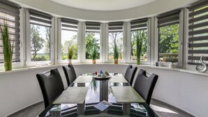 Un comedor con una mesa de vidrio, sillas negras y plantas en macetas.
