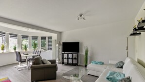 Una sala de estar moderna con un sofá, una mesa de centro de vidrio y un televisor de pantalla plana.
