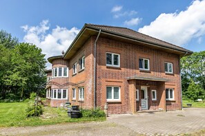 Une maison à deux étages, construite en briques, avec une allée pavée et un petit jardin.