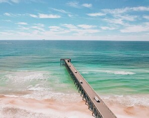 A pier extending into a calm sea with clear water and a sandy beach. - Grand Lagoon Vista -air hockey- Dreamy Day (Panama City Beach)