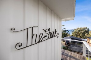 Un senyal metàl·lic amb la frase 'The Shack' a una paret blanca.