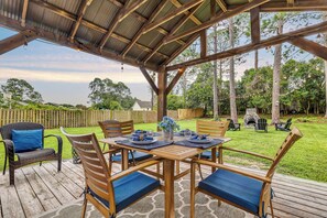 A covered outdoor patio with wooden furniture, a table set for dining, and a stone fireplace in the background. - Quiet escape in Wilmington (Wilmington)