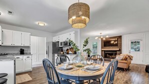 Een moderne keuken met witte kasten, een eethoek met een ronde tafel en een open haard.