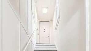 A white staircase with a handrail, leading to a door at the top.
