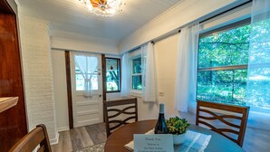 A dining area with a round table, chairs, a placemat, a bottle, and a sign. - The Dutch Getaway (Pensacola)