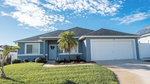 A single-story house with a garage, a front lawn, and a palm tree. - New! Themed rooms, Heated pool with private fenced yard, Pet friendly! (Davenport)