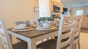 A dining area with a wooden table set for four, surrounded by white chairs. - New! Themed rooms, Heated pool with private fenced yard, Pet friendly! (Davenport)
