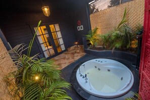 Un área de spa con un jacuzzi, rodeado de plantas y una pared de madera oscura.